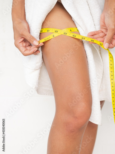 Foto Authentic skin tan and slim fit woman measuring her leg with white towel on white background