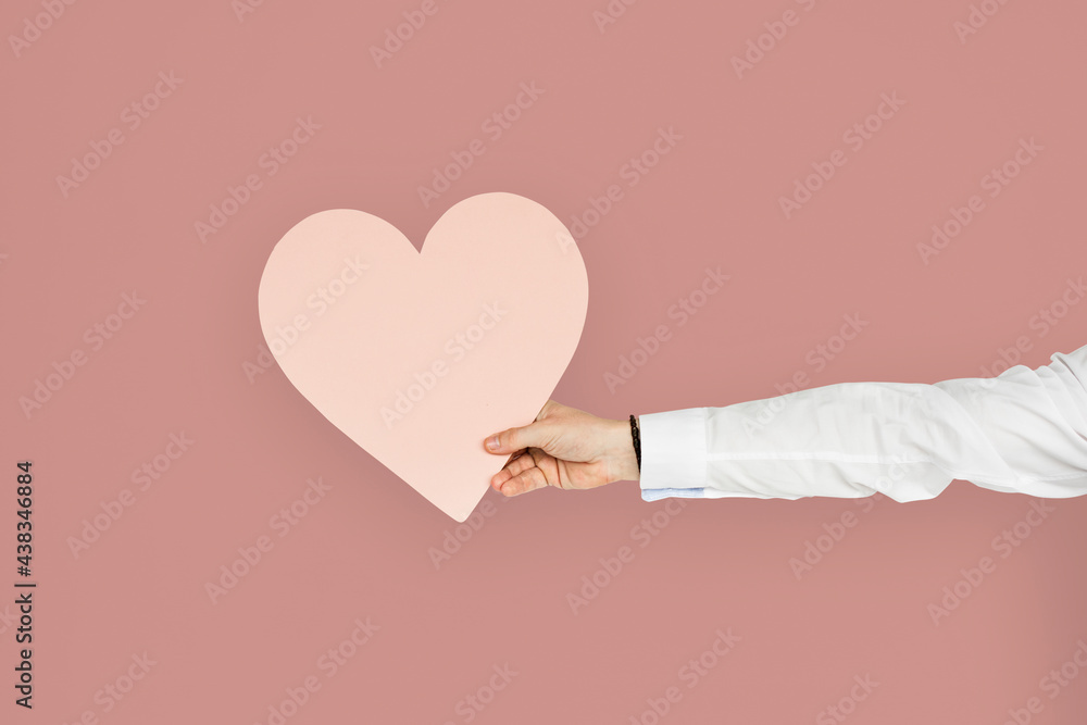 Hand holding a pink heart cutout, healthy heart or love concept Hand holding a pink heart cutout, healthy heart or love concept