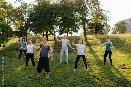 A group of people do yoga in the Park at sunset. Healthy lifestyle, meditation and Wellness © Andrii