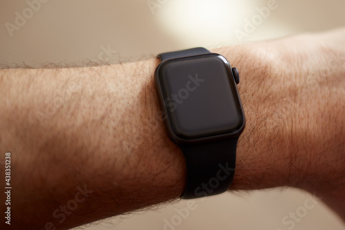 Smart watch on a man's hand, black screen, light background.