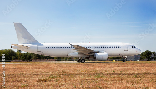A white plane on the airport runway is taxiing. Takeoff and landing. Arrival and departure. Place for text. Passenger plane mockup. Airplane flight. Travel by air transport. Copy space