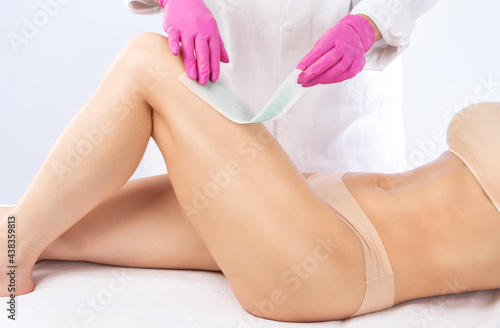 A beautician makes a sugar paste depilation of a woman's legs in a beauty salon. Female aesthetic cosmetology.