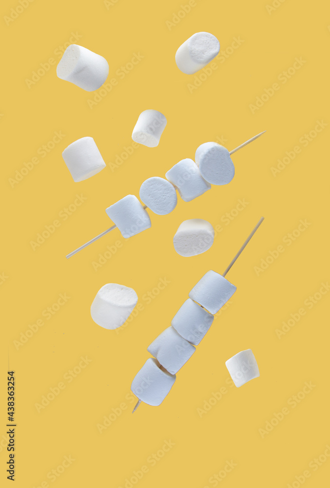flying food concept - marshmallows on skewers levitating against yellow background flying food concept - marshmallows on skewers levitating against yellow background
