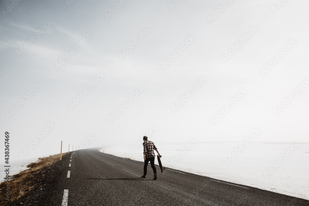 Man riding skateboard along countryside road Man riding skateboard along countryside road