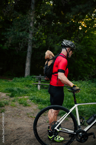 Man carrying dog in backpack pet carrier on a bike trip
