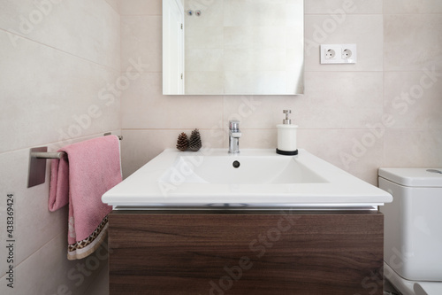 Front image of small bathroom with countertop  towel rack  mirror and toilet