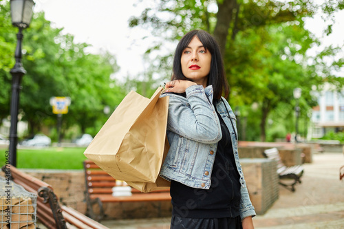 Woman holding several paper bags walking outdoors in the park