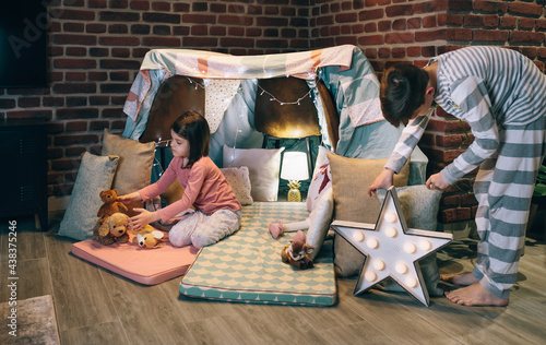Male teenager helping little sister prepare a diy tent for pajama party