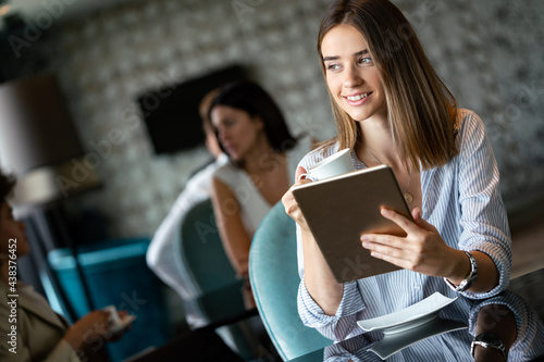 Happy woman manager holding tablet and sitting in cafe