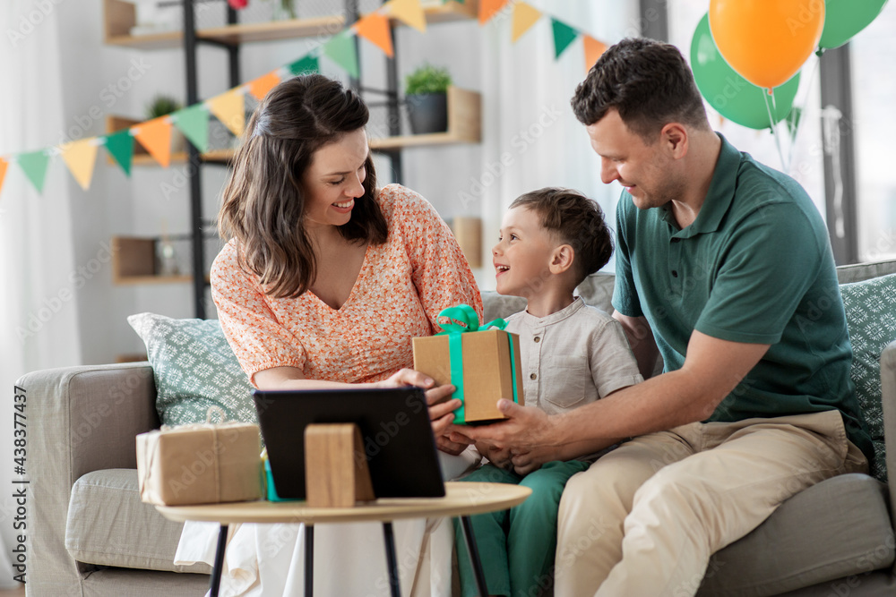 family, holidays and people concept - portrait of happy mother and father giving birthday present to little son sitting on sofa at home party family, holidays and people concept - portrait of happy mother and father giving birthday present to little son sitting on sofa at home party