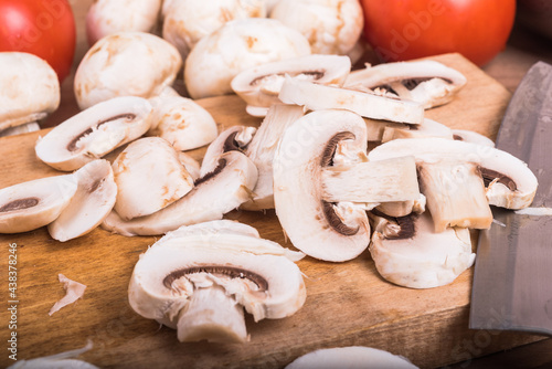 Sliced mushrooms on a cutting board kitchen for cooking tomatoes sautéed mushrooms and a tomato, close-up, close-up