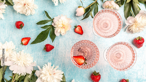 Fototapeta Naklejka Na Ścianę i Meble -  Rose wine in glasses with Peony Flowers and sweet fresh strawberries on blue background, Summer drink for party, wine shop or wine tasting concept