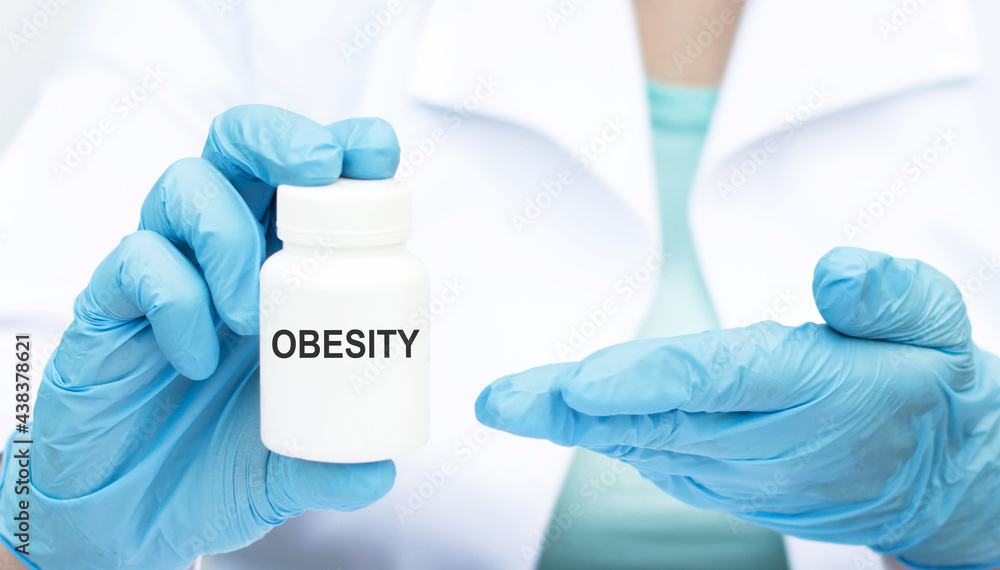 Fototapeta premium Close-up of a hands doctor in gloves with a white medicine jar on which the text OBESITY