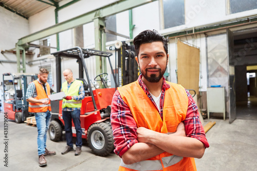 Warehouse worker with crossed arms in front of forklift truck photo