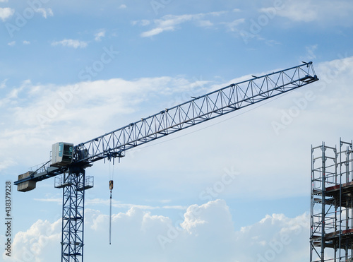 Construction tower crane machine in low-angle perspective with blue sky and clouds in background