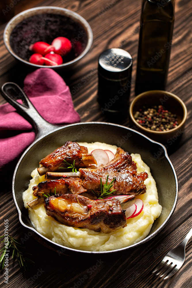 Oven-roasted pork ribs with mashed potatoes on a wood table. Top view, vertical image. Oven-roasted pork ribs with mashed potatoes on a wood table. Top view, vertical image.