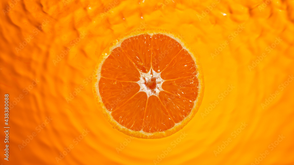 Fresh orange slice falling into splashing water splashing, top view. Fresh orange slice falling into splashing water splashing, top view.
