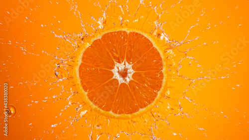Fresh orange slice falling into splashing water splashing, top view.