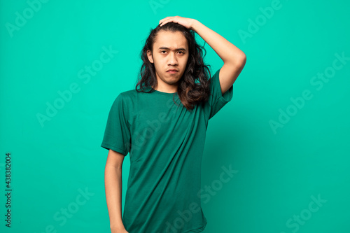 young man with long hair  with a serious face isolated on blue background © Danykur
