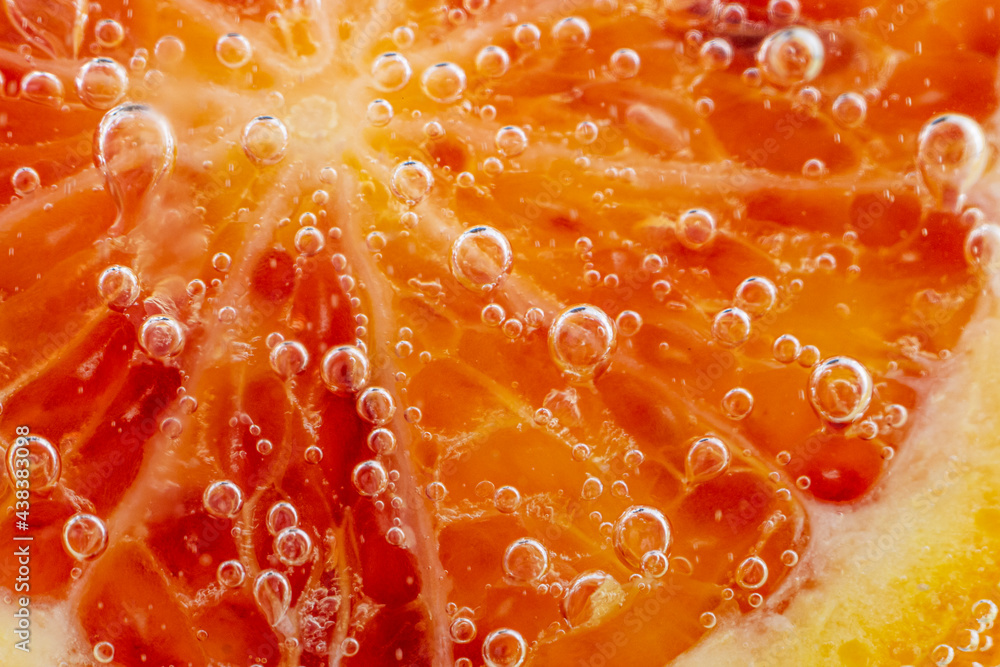 Grapefruit close-up in liquid with bubbles. Slice of blood red ripe grapefruit in water. Part of set. Grapefruit close-up in liquid with bubbles. Slice of blood red ripe grapefruit in water. Part of set.