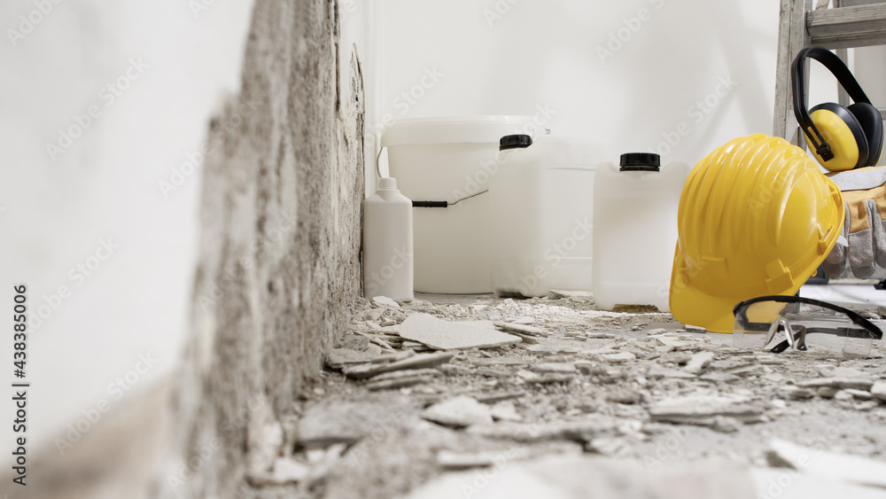 house renovation concept, wall in demolition with plaster rubble and protective construction work tools, paints, primer, buckets and jerry cans of building products, white background with copy space - obrazy, fototapety, plakaty 
