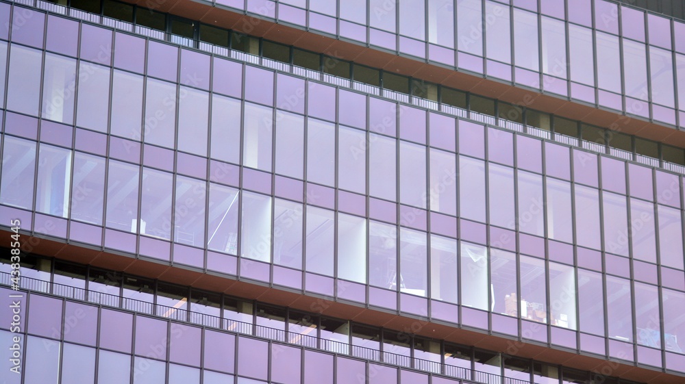 Fototapeta premium Abstract closeup of the glass-clad facade of a modern building covered in reflective plate glass. Architecture abstract background. Glass wall and facade detail.