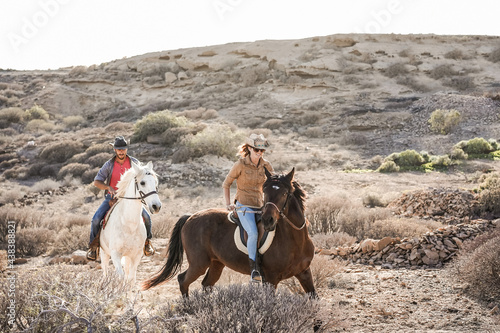 Obraz na plátne Young people riding horses doing excursion at sunset - Main focus on woman face