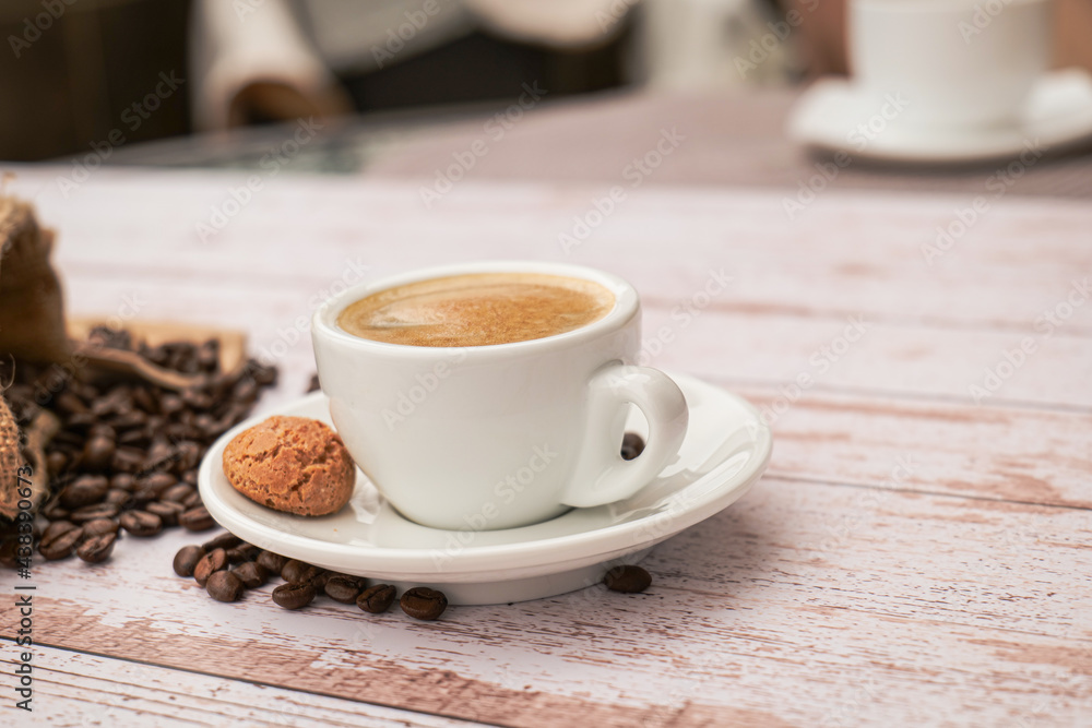 Fototapeta premium Cup of coffee with beans on a light wooden table.