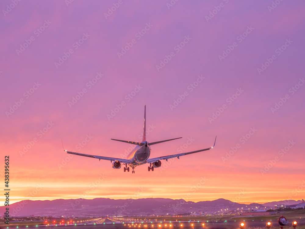 美しい夕焼けを背景に着陸する飛行機のイメージ