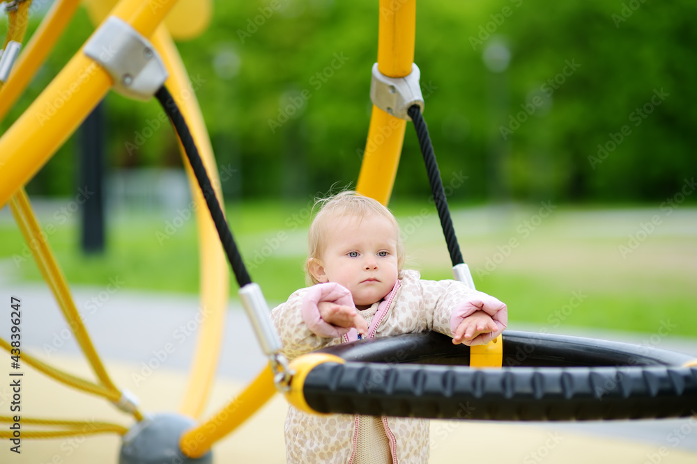 Cute toddler baby having fun on outdoor playground. Adorable little girl is swinging. Kindergarten, daycare, nursery for small children. Spring/summer/autumn active leisure for kids. Cute toddler baby having fun on outdoor playground. Adorable little girl is swinging. Kindergarten, daycare, nursery for small children. Spring/summer/autumn active leisure for kids.