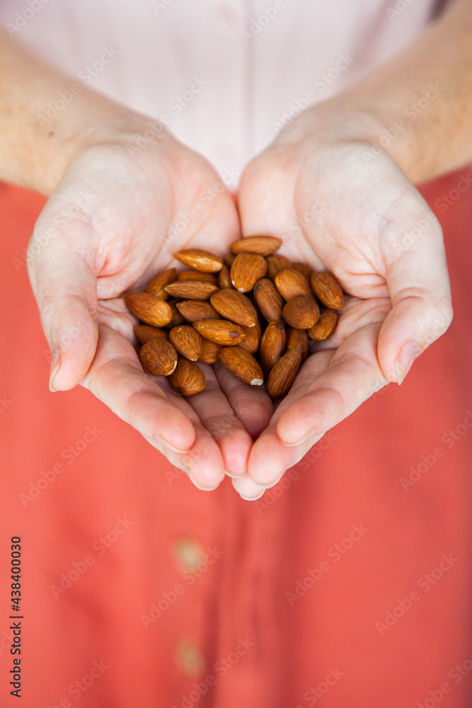 Person holding healthy snack of almond nuts in her hands Person holding healthy snack of almond nuts in her hands