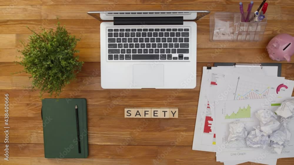 Word safety is made from wooden cubes by hands on an office table next to papers and a laptop. Safety and security concept. Word safety is made from wooden cubes by hands on an office table next to papers and a laptop. Safety and security concept.