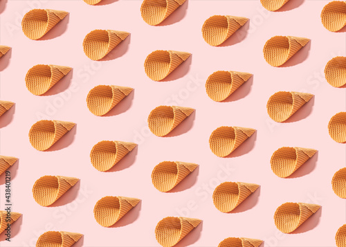 Minimal summer pattern made of empty ice cream cones on sunny pink background.