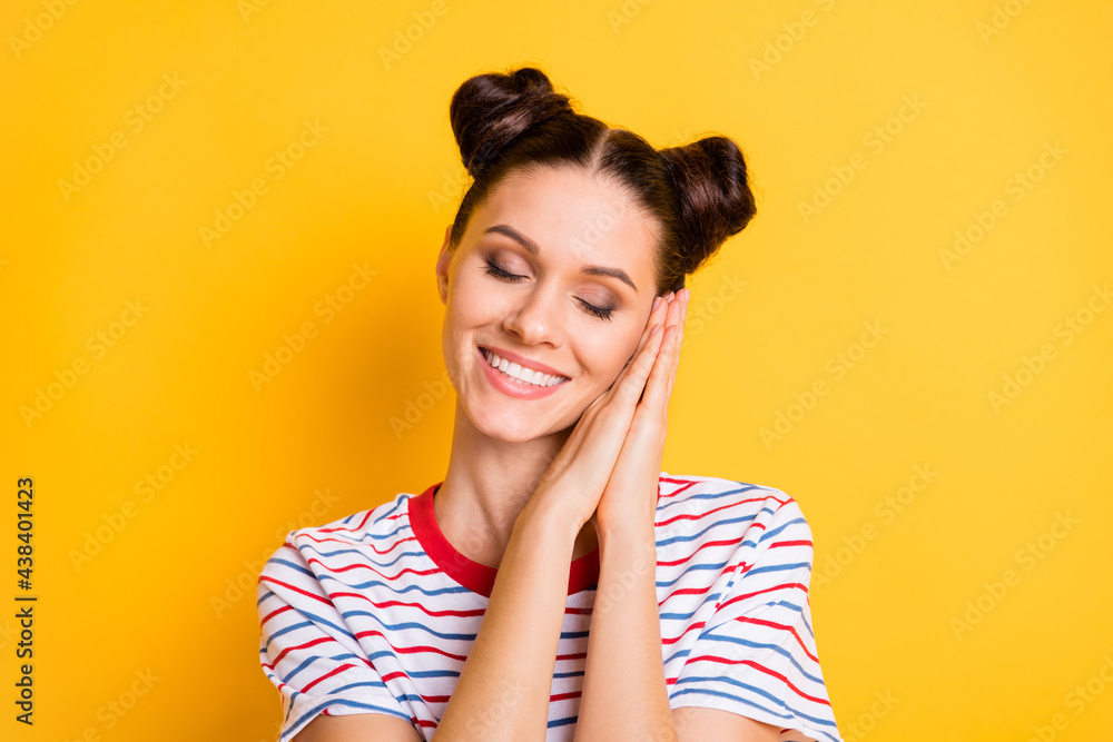 Photo of sweet adorable young lady wear striped t-shirt hands cheek closed eyes isolated yellow color background Photo of sweet adorable young lady wear striped t-shirt hands cheek closed eyes isolated yellow color background