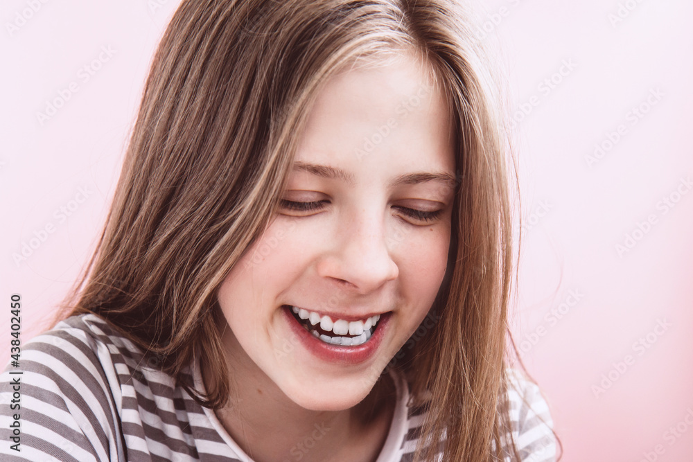 Face of a beautiful smiling teenage girl with long hair on pink background. Happy girl dreams Face of a beautiful smiling teenage girl with long hair on pink background. Happy girl dreams