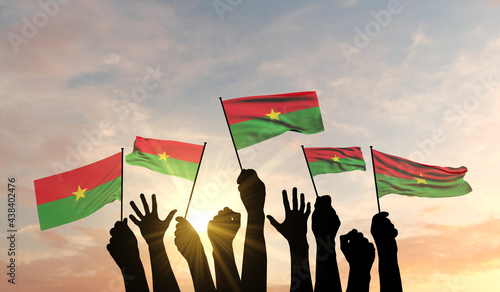 Fényképezés Silhouette of arms raised waving a Burkina Faso flag with pride