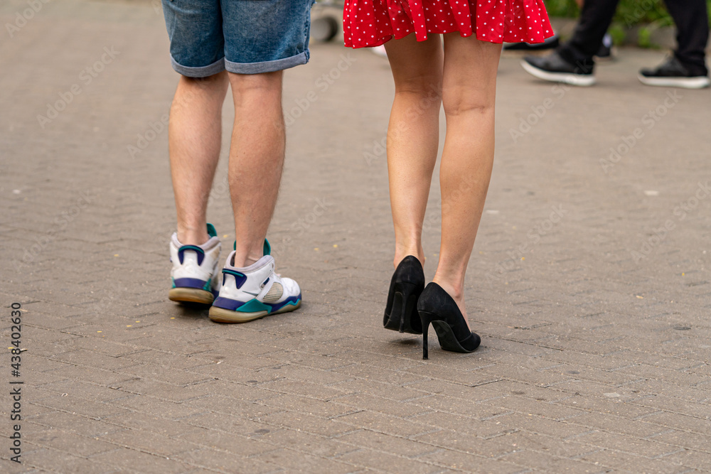 Legs of a woman in a mini skirt and a man in shorts and sneakers