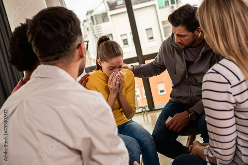 Diverse group of people sitting in circle in group therapy session.