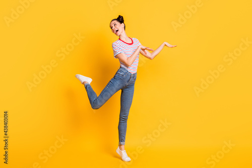 Photo of funny funky young lady dressed striped outfit dancing isolated yellow color background