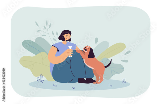 Happy girl sitting and feeding dog with bone. Woman playing, training puppy and giving treatment to pet flat vector illustration. Owner, friend concept for banner, website design or landing web page