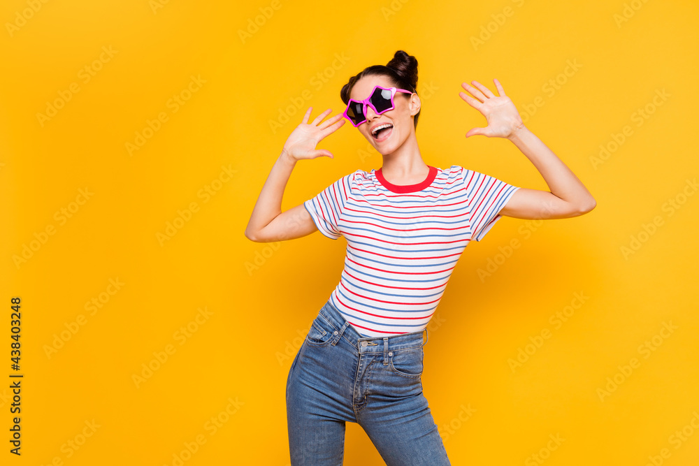 Photo of shiny funny young girl dressed striped t-shirt dark glasses dancing empty space isolated yellow color background Photo of shiny funny young girl dressed striped t-shirt dark glasses dancing empty space isolated yellow color background