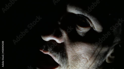 Time lapse of ugly scary devil man in half-light with chiaroscuro, scary and mysterious man screaming while opening his mouth, horror movie and macabre atmosphere