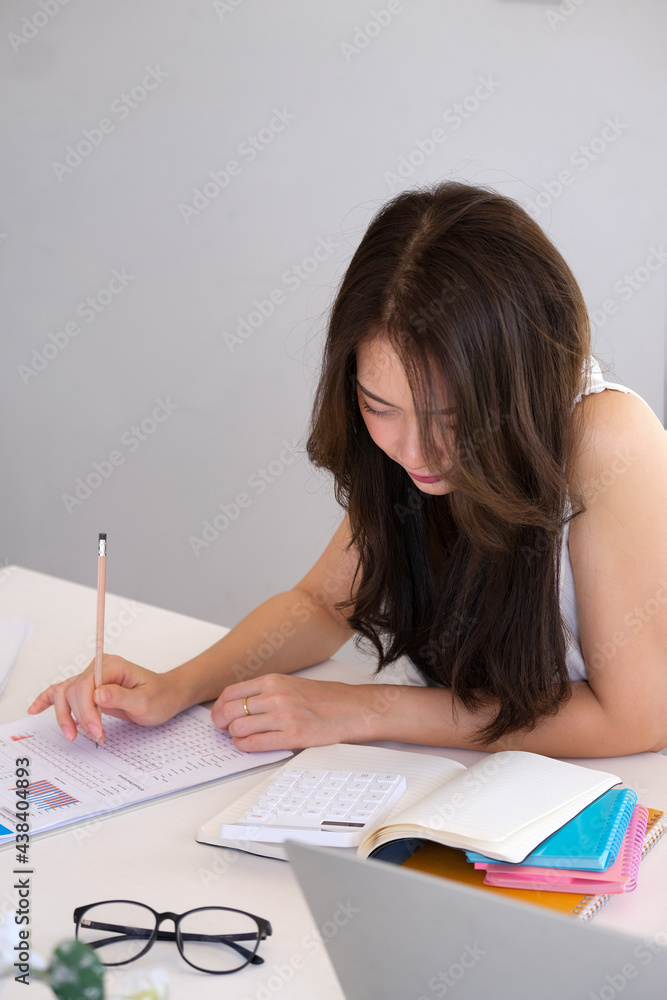 Business women use data and calculator for data analysis with notebook and laptop. Business women use data and calculator for data analysis with notebook and laptop.