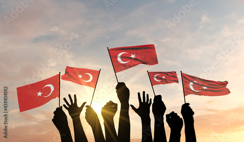 Photos Silhouette of arms raised waving a Turjey flag with pride