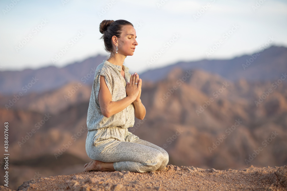 Woman practicing yoga in the mountains in the desert Woman practicing yoga in the mountains in the desert