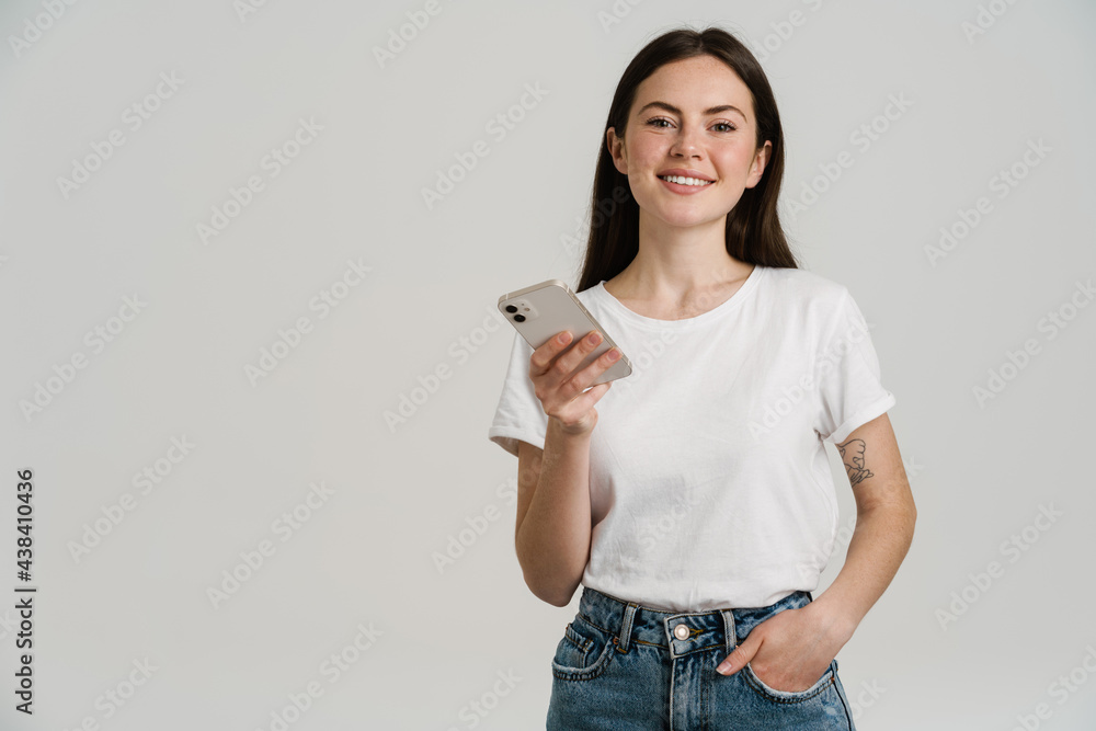 Young brunette woman in t-shirt smiling while using mobile phone Young brunette woman in t-shirt smiling while using mobile phone