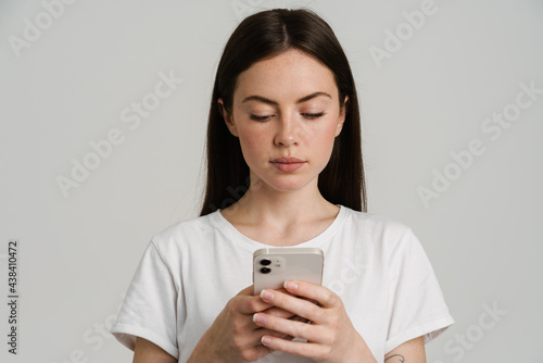 Young brunette woman in t-shirt using mobile phone