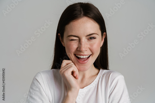 Young brunette woman winking and laughing at camera photo