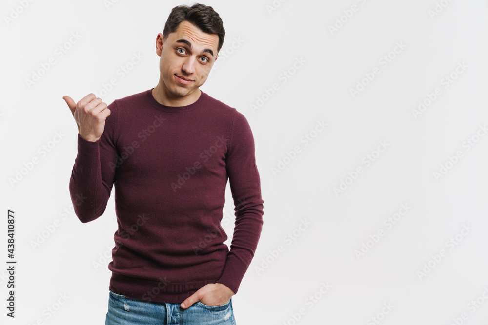 Young brunette man looking and pointing finger aside Young brunette man looking and pointing finger aside