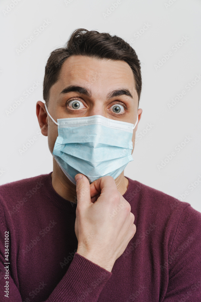Young brunette shocked man in face mask looking at camera Young brunette shocked man in face mask looking at camera
